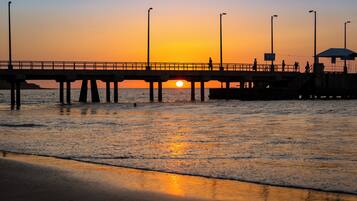 A pier extending into calm waters with a sunset in the background.