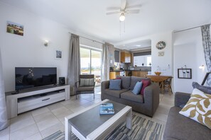 Ein modernes Wohnzimmer mit Flachbildfernseher, einer Couch, einem Couchtisch und einem Essbereich mit Tisch und Stühlen.
