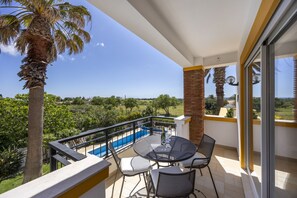 A balcony with a pool, outdoor furniture, and a view of the landscape. - Villa A Jardim Palmeiras Condominium by CoolHouses (Luz)