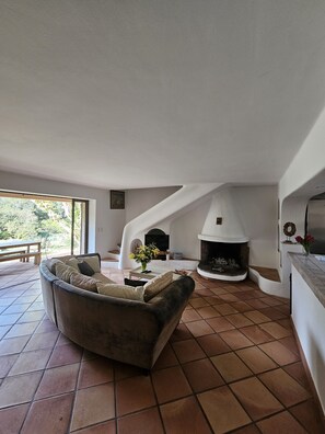 Relax in this inviting living area with a fireplace, comfortable sofa, and garden views.
