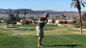 A man in a golf uniform preparing to swing at a golf course with a clear sky and mountains in the background. - Clean 3 Bed/2 bath home w/ pool, BBQ & covered patio, locked RV & boat parking (Lake Havasu City)