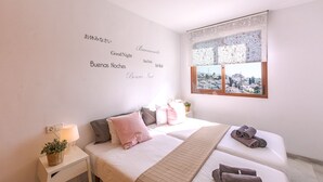 Une chambre d’hôtel avec un lit, des tables de chevet, une lampe et une vue sur le paysage urbain par la fenêtre.