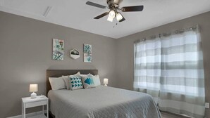 A bedroom with a bed, a ceiling fan, a nightstand, and a window with curtains. - The Bittersweet Inn: Brand new 6 bed 5 bath house (Hermann)