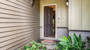 A house entrance with a dark brown door, a mailbox, and a small garden area with plants.