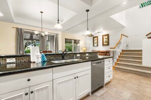 A modern kitchen with a central island, white cabinetry, and a built-in dishwasher. - 🏖️Mauna Lani Townhome with Private Beach Club Access | Kulalani 404 (Kamuela)