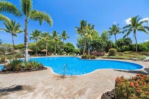 A swimming pool surrounded by palm trees and greenery, with lounge chairs and a small building in the background. - 🏖️Mauna Lani Townhome with Private Beach Club Access | Kulalani 404 (Kamuela)