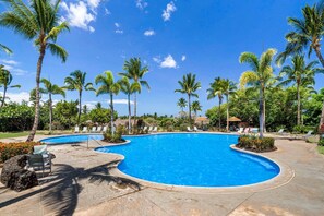Piscina com espreguiçadeiras e palmeiras.