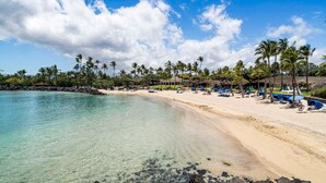 A beach with clear water, palm trees, and a building with a roof. - 🏖️Mauna Lani Townhome with Private Beach Club Access | Kulalani 404 (Kamuela)