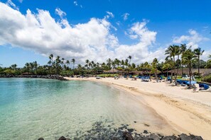 A beach with clear water, palm trees, and a building with a roof. - 🏖️Mauna Lani Townhome with Private Beach Club Access | Kulalani 404 (Kamuela)