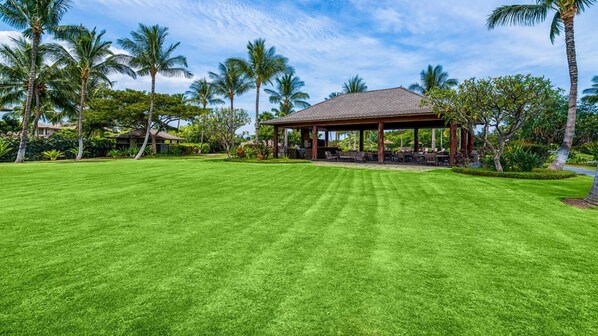 A well-maintained lawn with a gazebo and palm trees.