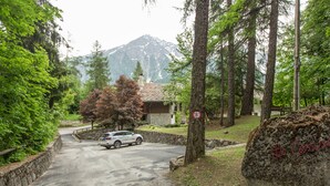 A road leading to a building with a stone wall and a large rock with text.
