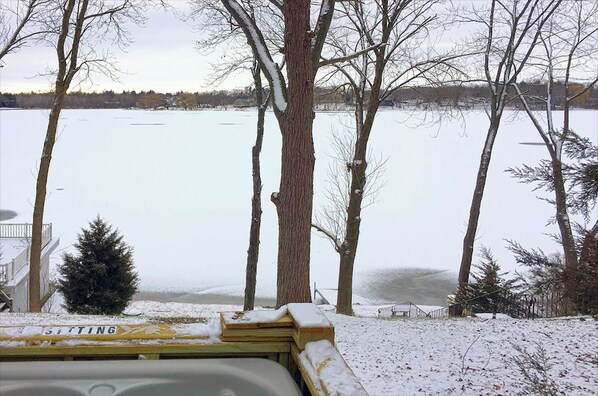 Une vue d’un lac entouré d’arbres, avec un panneau indiquant « ASSEOIR » au premier plan.