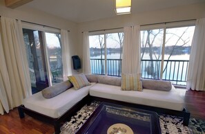 Relax in this stylish living room with a large sofa, glass coffee table, and serene views of a body of water.