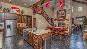 A spacious kitchen with a central island, a stone fireplace, and a wooden staircase. - Lone Star State of Mind - 6BD/5BA w/ FIshing Pond & Fully Furnished Kitchen (Sherman)