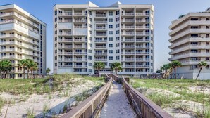 A beachfront hotel with multiple floors, balconies, and a sandy walkway leading to the beach. - Toes In the Sand!!! (Pensacola)