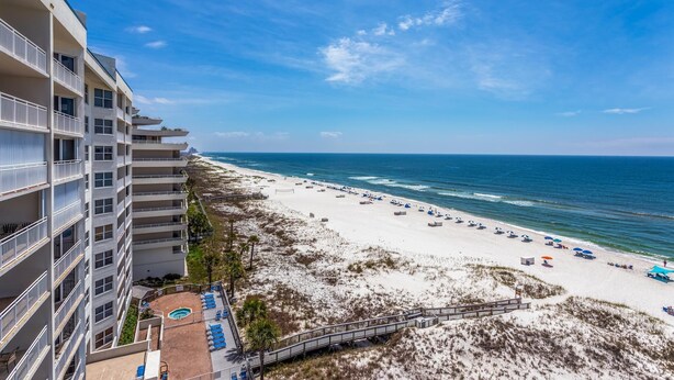 A beachfront hotel with multiple balconies, a sandy beach, and a clear blue sky. - Toes In the Sand!!! (Pensacola)