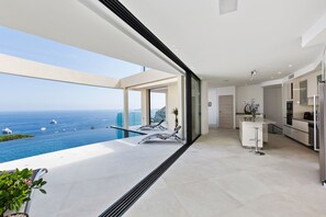 Een moderne keuken met uitzicht op de oceaan, een balkon met zwembad en een eethoek.