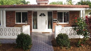 A two-story house with a brick facade, a white door, and a tiled roof.