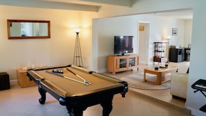 Ein Wohnzimmer mit Billardtisch, Fernseher und einer kleinen Essecke.