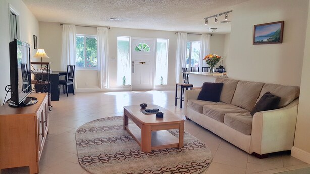 A spacious living room with a sofa, coffee table, and a dining area with chairs and a table.