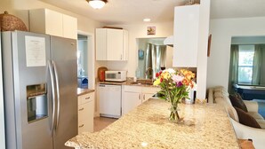 A modern kitchen with white cabinets, stainless steel appliances, and a granite countertop.
