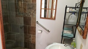 Une salle de bain équipée d’une douche, d’un lavabo, de toilettes, d’un porte-serviettes et d’un miroir.