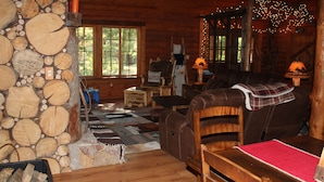 A cozy cabin interior with a stone wall, wooden furniture, and a fireplace. - Cozy, Family Friendly Log Cabin Close To Everything! (Williams Bay)