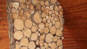 A log fireplace with a stone surround, a television on a wooden stand, and a window with a view of the outside. - Cozy, Family Friendly Log Cabin Close To Everything! (Williams Bay)