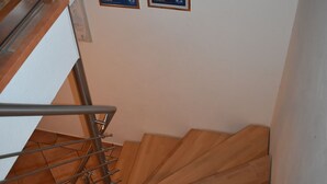 Un escalier en bois avec des rampes en métal et une série de plaques encadrées accrochées au mur.