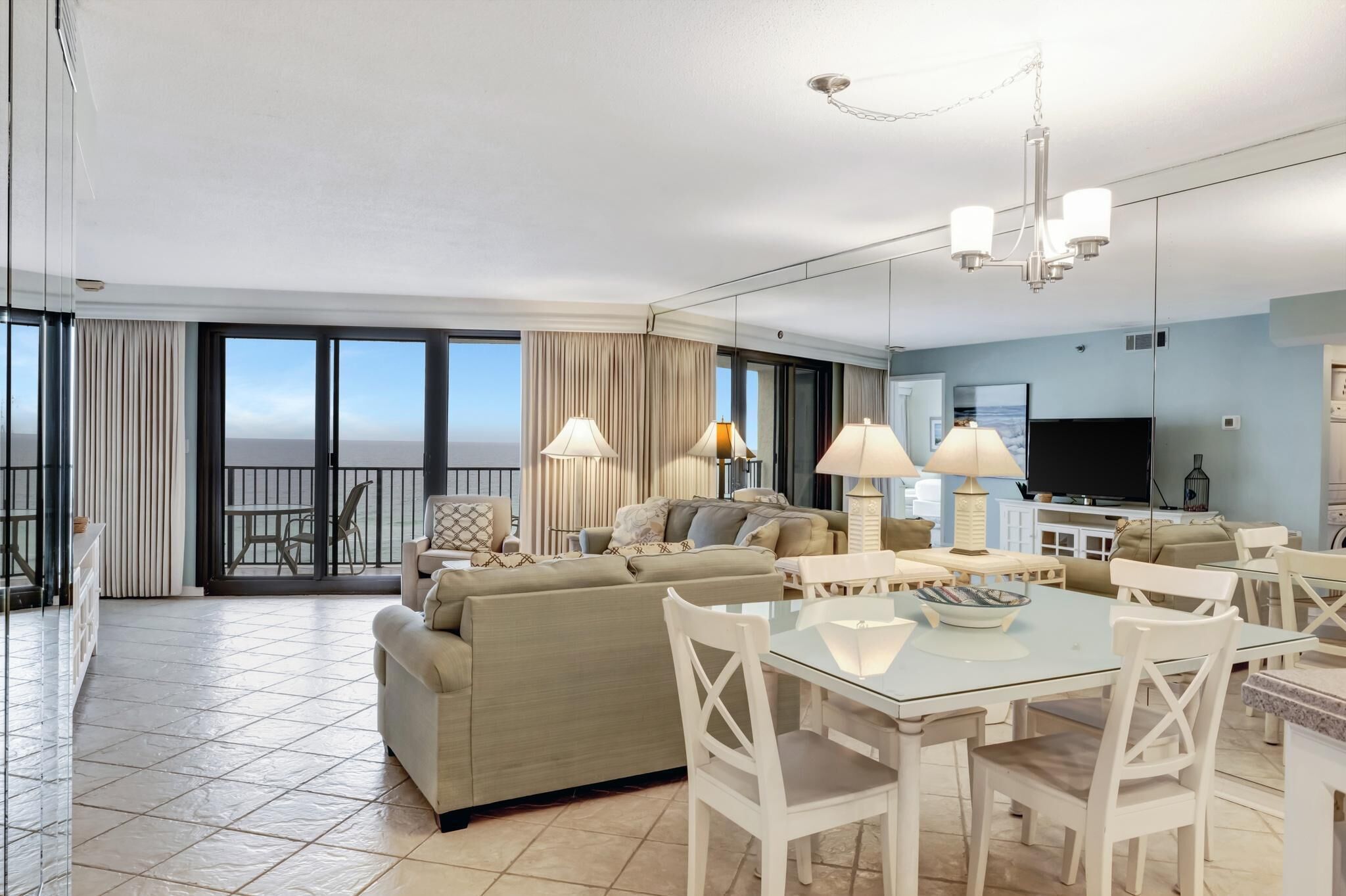 A modern hotel room with a balcony, a dining area, and a living room.