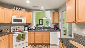 A kitchen with wooden cabinets, a microwave, stove, and a dishwasher. - GOIN COASTAL Beach House, 3/2, Sleeps 10, 3 min Walk To The Beach  (St. Augustine)