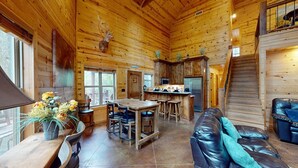 A log cabin interior with a dining area, kitchen, and a staircase. - Yellow Rose Cabin: Pet-Friendly Hochatown Getaway (sleeps 12) w/ Hot Tub, Arcade (Broken Bow)