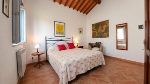 A bedroom with a bed, a radiator, a window, and artwork on the walls. - Zolferate: peaceful romantic cottage with private garden (Roccalbegna)