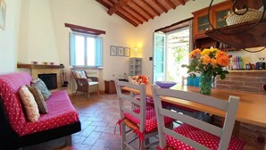 Una sala acogedora con sofá, sillones, una mesa de comedor y un área de cocina con ventana.