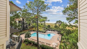 A pool area with lounge chairs and a view of the beach.