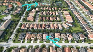An aerial view of a residential area with uniform houses, roads, and green spaces.