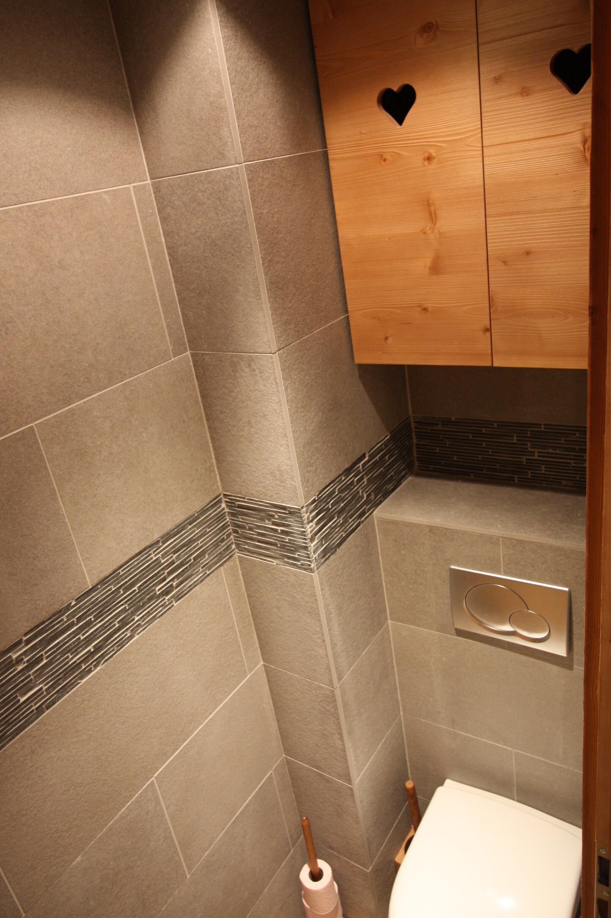 A bathroom with a toilet, a hand dryer, and a towel rack.
