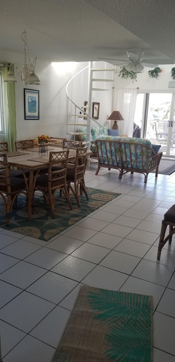 A spacious living area with a dining table, chairs, a sofa, and a ceiling fan. - Anchorage Condo, East End - Views, pool, beach, and bliss. (St. Thomas VI)