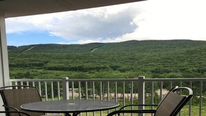 A balcony with a table and chairs overlooking a forested hillside. - River Walk Resort at Loon studio, kitchenette, balcony, mount, river view, 5 fl (Lincoln)