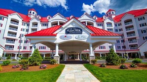 A hotel with a red roof and white exterior, featuring a central entrance with a sign for 'Riverwalk' and 'La Voya'. - River Walk Resort at Loon studio, kitchenette, balcony, mount, river view, 5 fl (Lincoln)