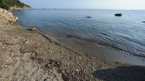 A rocky shoreline with clear water and distant land.
