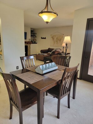 A dining area with a wooden table, chairs, and a hanging light fixture.