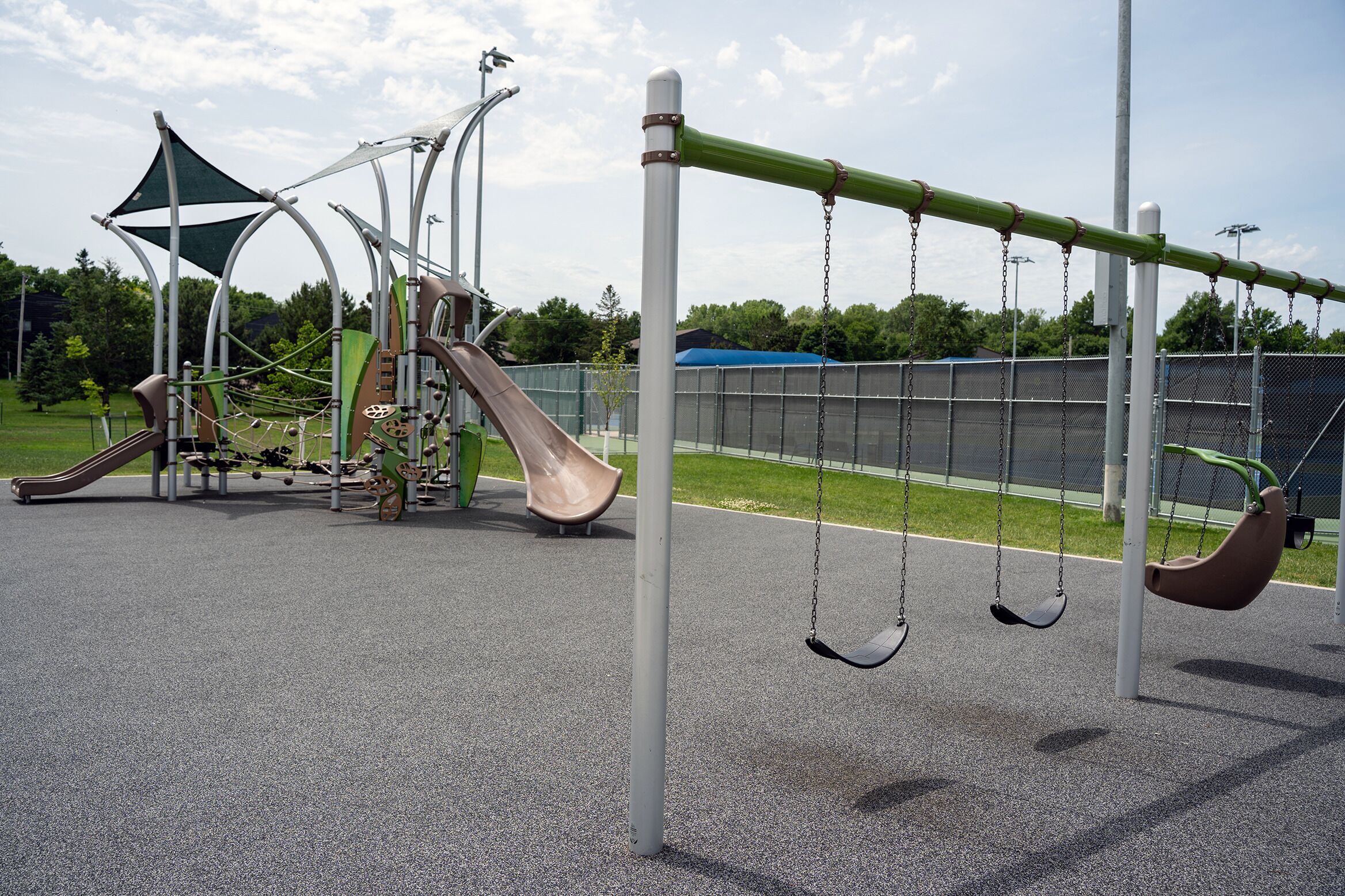 Une aire de jeux avec des balançoires, un toboggan et des structures d’escalade.