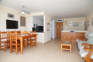 A spacious living area with a dining table, chairs, a sofa, and a kitchen in the background.