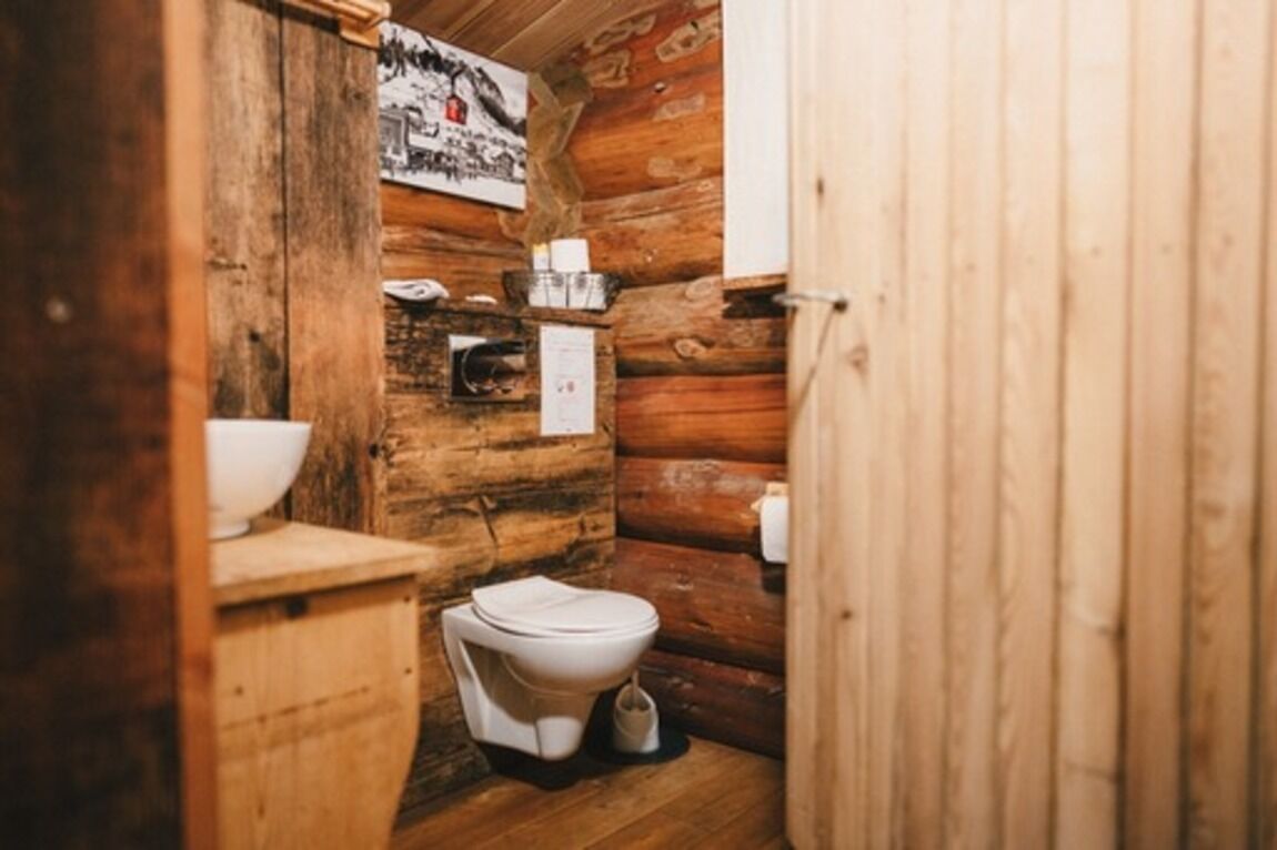 A rustic wooden bathroom with a toilet, sink, and a poster on the wall.