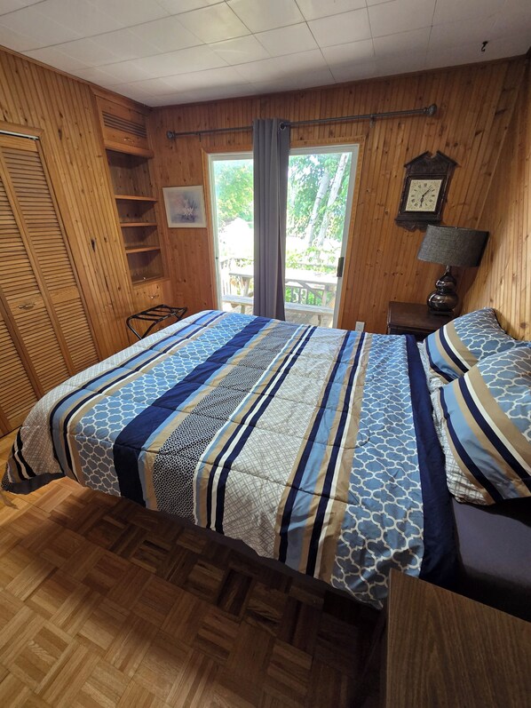 A room with a bed, a wooden wardrobe, a small table with a lamp, and a window with curtains. - Kawartha's Home/Cottage on Buckhorn Lake (Ennismore)
