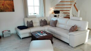 Ein modernes Wohnzimmer mit einem Ecksofa, einem Couchtisch und einer Treppe.
