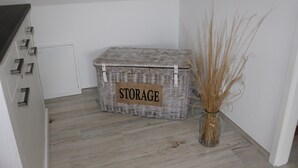 Eine Aufbewahrungsbox mit dem Aufdruck 'STORAGE' steht in einer Ecke mit Holzboden und einer Vase mit getrockneten Pflanzen.