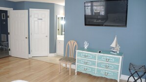 A bedroom with a bed, a dresser, a chair, and a TV on the wall.
