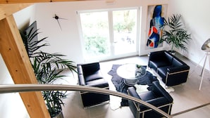 Una sala de estar moderna con un sofá de cuero negro, una mesa de centro de vidrio y un amplio ventanal que ofrece vistas al exterior.